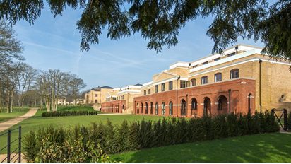 Restored brick buildings at Bentley Priory, Stanmore, beyond a lawn