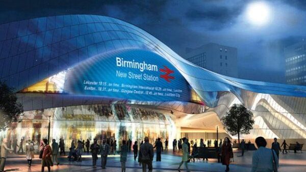 Curved stainless-steel entrance of Birmingham New Street station at night