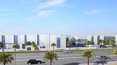 Low white data-centre buildings of Khazna Data Centre beside a palm-lined road