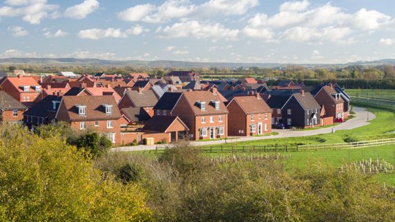 Red-brick homes at Kingsbrook, Aylesbury, seen across open green space